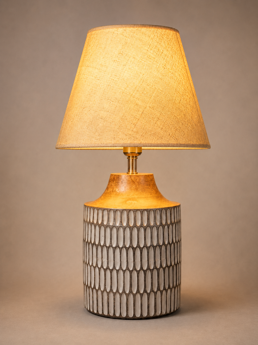 Table lamp with textured shade and patterned base on a beige background