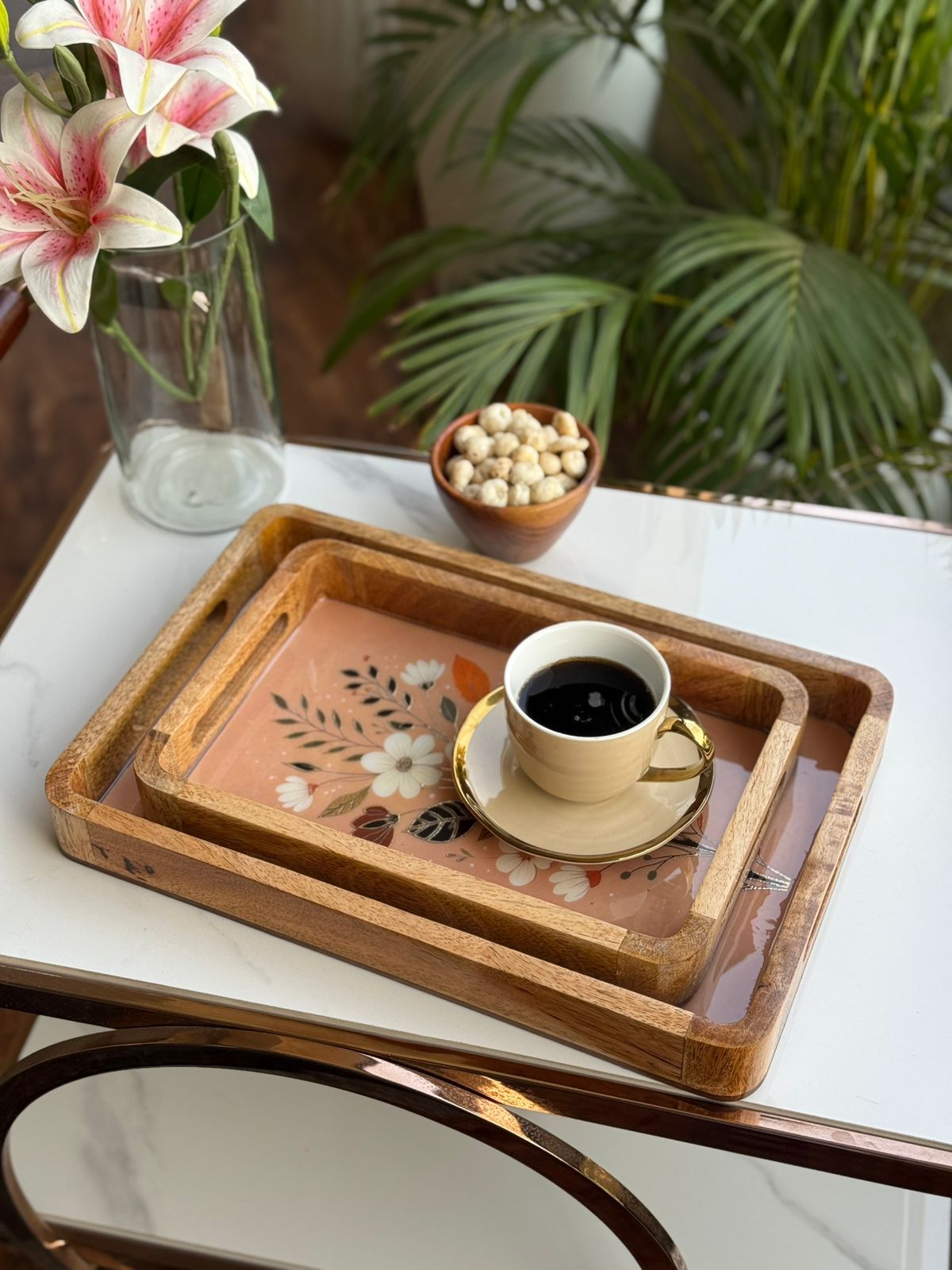 Cup of coffee on a decorative tray with flowers and plants in the background