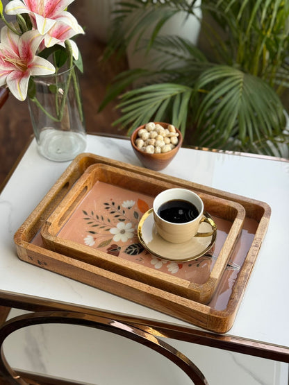 Cup of coffee on a decorative tray with flowers and plants in the background