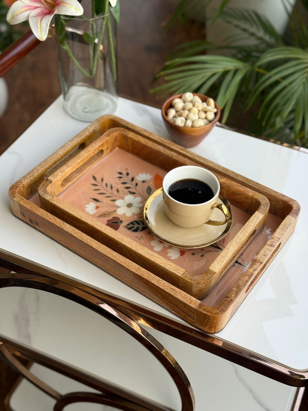 Wooden tray with floral design holding a cup of coffee on a marble surface.